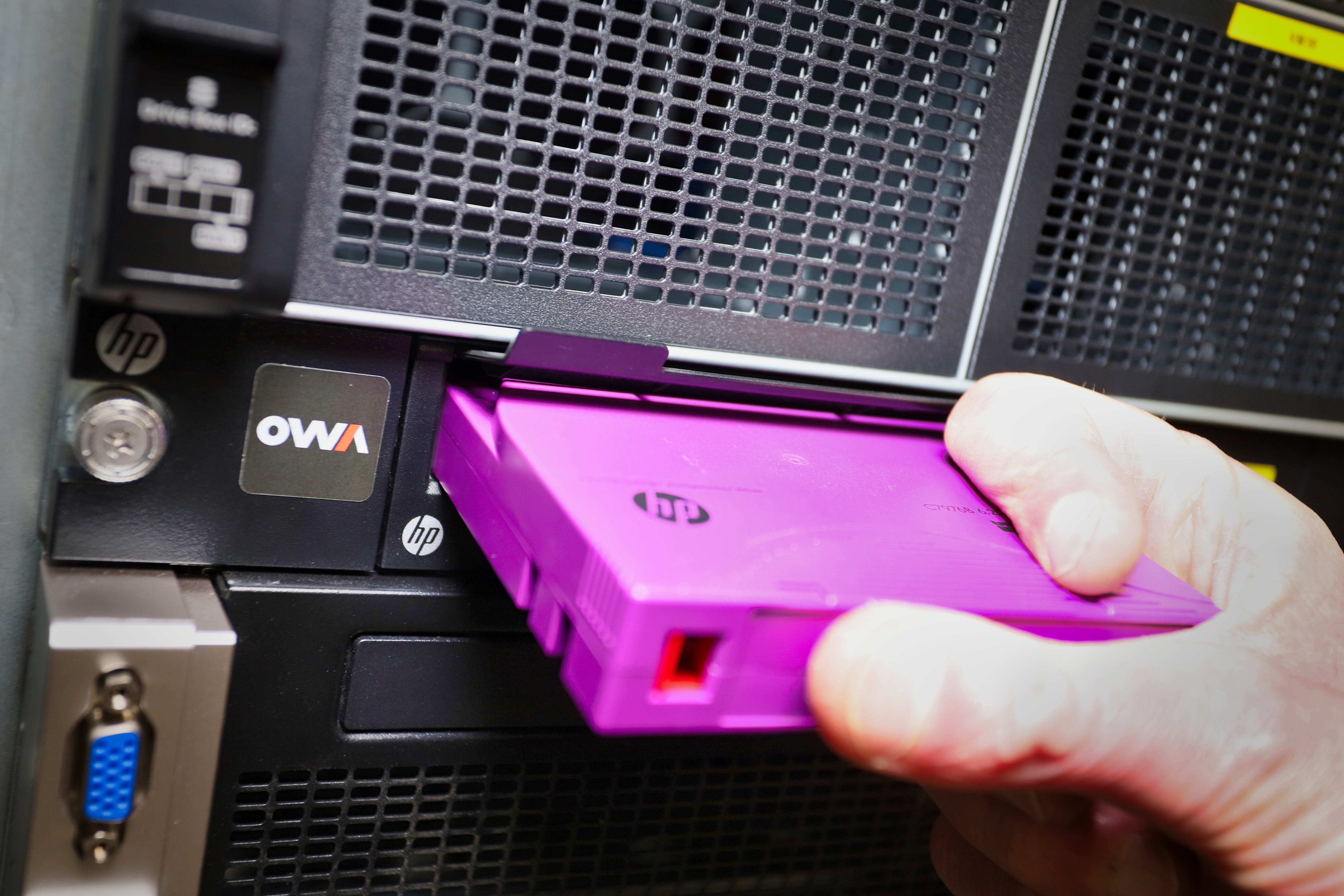 A person holds a purple backup tape, just before it is inserted into a tape drive.