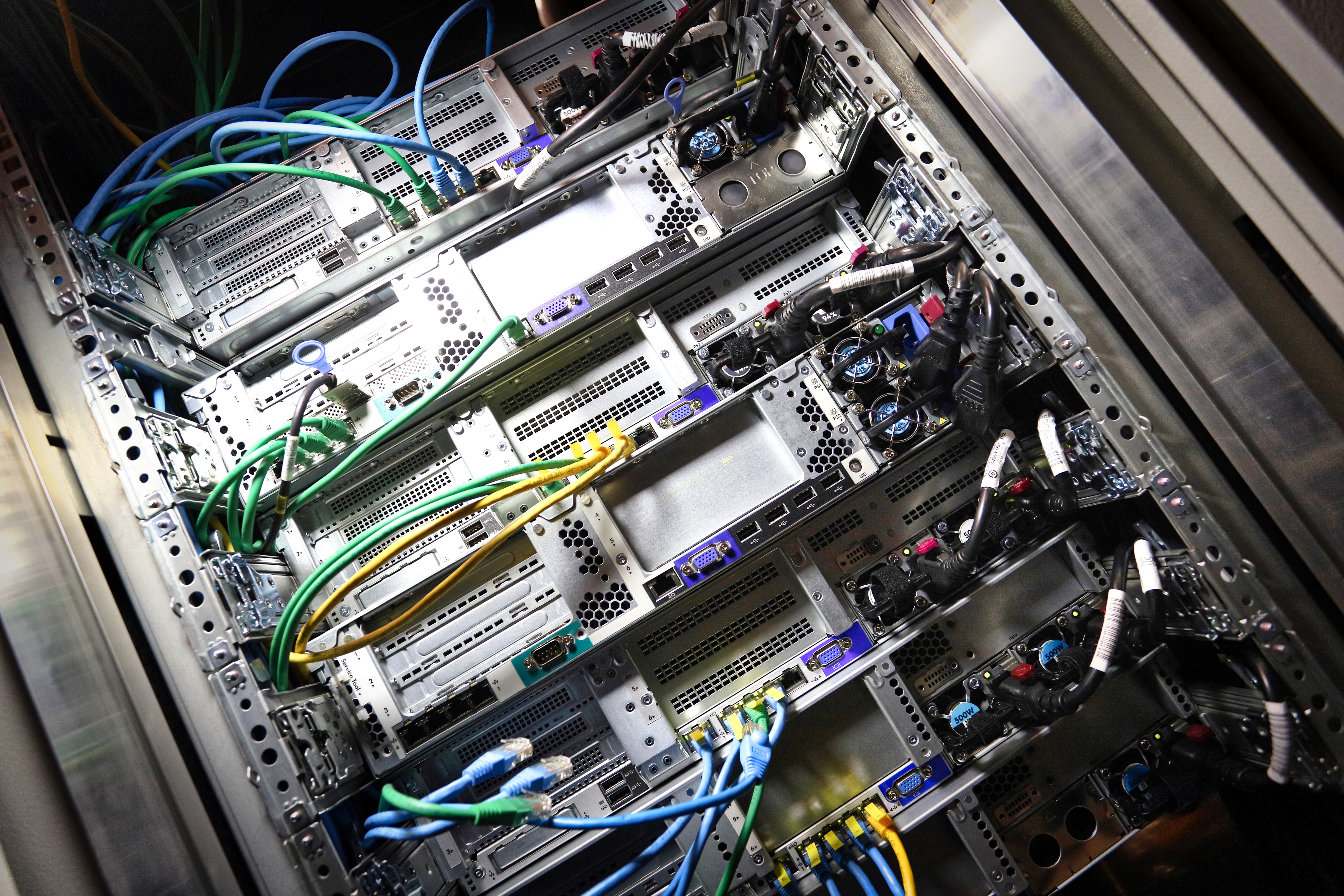 A server rack displaying multiple servers interconnected with numerous wires and cables for data management.