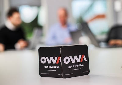 Interior of OWA Digital office with staff members in the background, emphasizing teamwork and innovation.